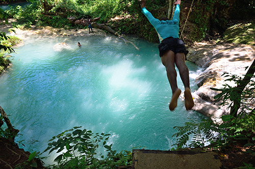 Devroe, our guide at the Blue Hole, leaps from a ledge into the turquoise water of the Blue Hole in Ocho Rios at the Jamaica port for Royal Caribbean's Navigator of the Seas on our Caribbean Cruise vacation